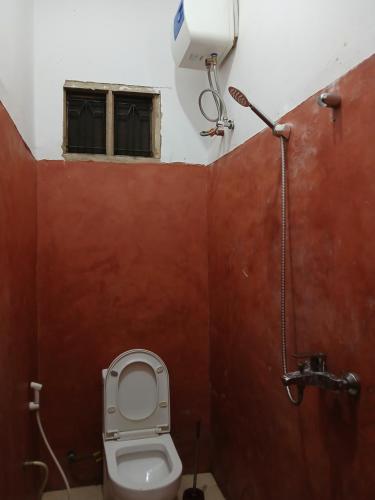 a bathroom with a toilet and a window at Naira House in Jambiani