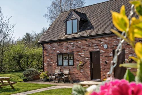 a brick house with a table and chairs in a yard at Charlie's Cottage with Alpacas and 7mins drive to Alton Towers in Denstone