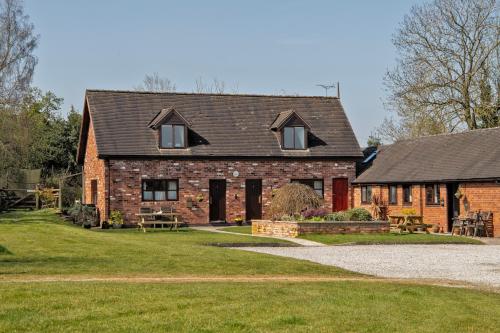 a brick house with windows and a grass yard at Charlie's Cottage with Alpacas and 7mins drive to Alton Towers in Denstone