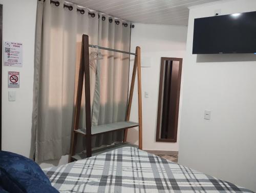 a room with a bed with a curtain and a tv at Pitaya Haus Lofts in Brusque