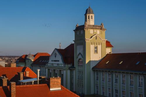 a large building with a tower on top of roofs at R73 Residences in Pécs