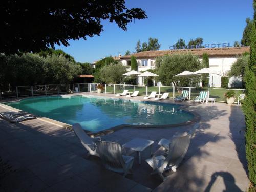 une grande piscine avec des chaises et une maison dans l'établissement Olivier Hôtel, à Vinon-sur-Verdon