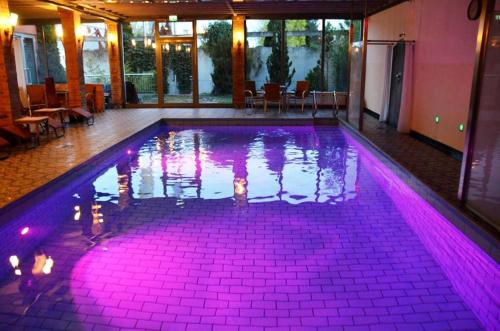 a swimming pool with purple lighting in a building at Ringhotel Alpenhof - Patchworkhotel in Augsburg