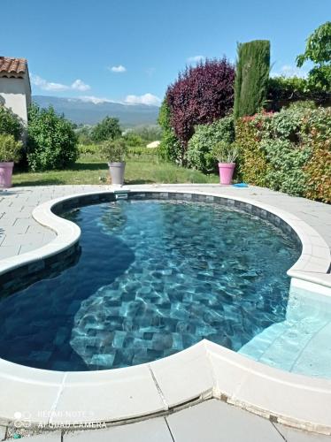 une piscine dans un jardin avec de l'eau bleue dans l'établissement Le Cabanon d'Amandine et Gabriel, à Blauvac