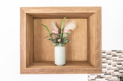 a white vase with flowers in a wooden frame at Ferienhaus Oberpremgut in Krispl