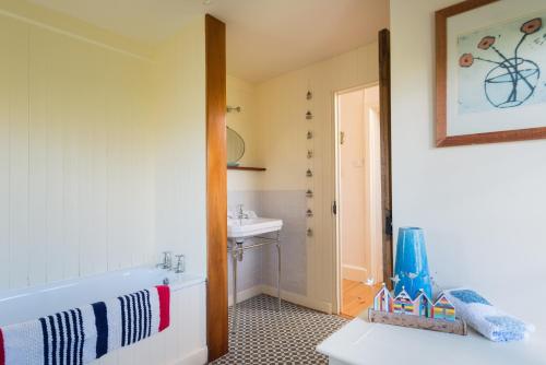 a bathroom with a bath tub and a sink at Trevigue Cottage in Bude