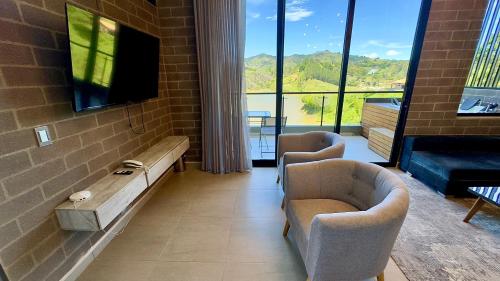 a living room with two chairs and a flat screen tv at Rooca Habitat Guatape in Guatapé