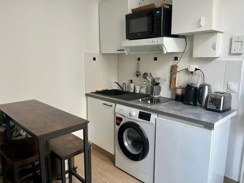 une cuisine avec un lave-linge et un micro-ondes dans l'établissement Appartement quartier Montorgueil, à Paris
