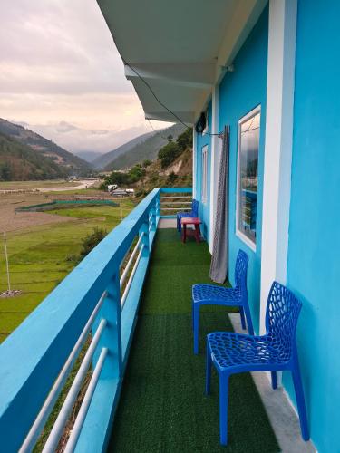 a balcony of a blue house with two chairs at Valley View Homestay in Dirang Dzong