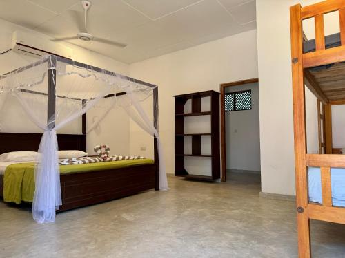 a bedroom with a bed with a canopy at Kudah Bay Surf Camp in Arugam Bay