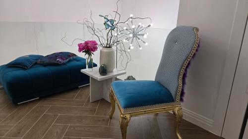 a room with a blue chair and a table with flowers at Villa Marmont Karlovac Luksuzni Smještaj na Top Lokaciji s Parkingom i Self Check inom in Karlovac