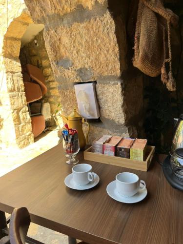 a wooden table with two cups and books on it at Hartna zaman in Taiyiba
