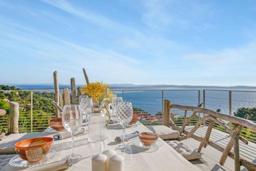 a table with glasses and a view of the ocean at La Vigie Mont des oiseaux Vue mer panoramique By HC in Hyères