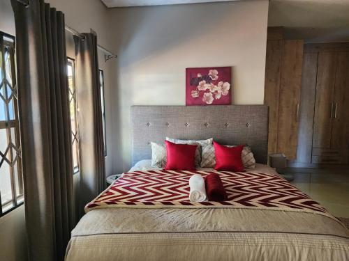 a bedroom with a large bed with red pillows at Eastern Road Executive Suites in Harare
