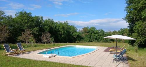 a swimming pool with two chairs and an umbrella at Grange avec piscine - La Hulotte du Cluzel in Montcléra