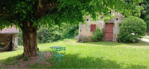 a table and chair under a tree in a yard at Grange avec piscine - La Hulotte du Cluzel in Montcléra