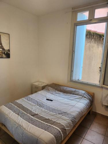 un lit dans une chambre avec une fenêtre dans l'établissement Pratique, à Sète