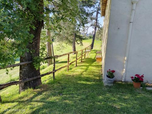 a fence next to a house with a tree at Podere Casone in SantʼAdriano
