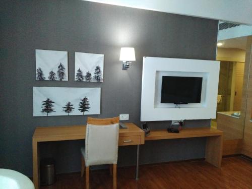 a room with a desk with a television and paintings at Maha Bodhi Hotel.Resort.Convention Centre in Bodh Gaya