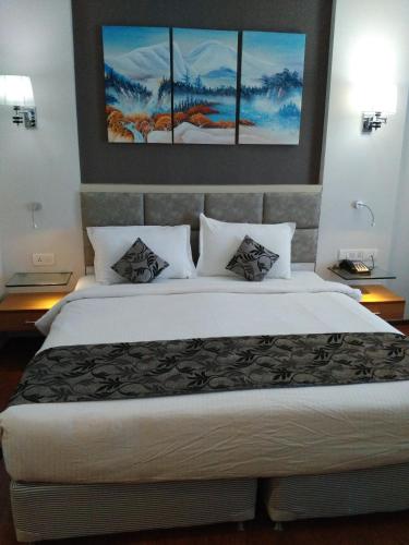 a bedroom with a large bed with three paintings on the wall at Maha Bodhi Hotel.Resort.Convention Centre in Bodh Gaya