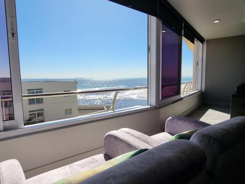a living room with two couches and a large window at Lagoon Shoreline 2 Bedroom Apartment in Cape Town