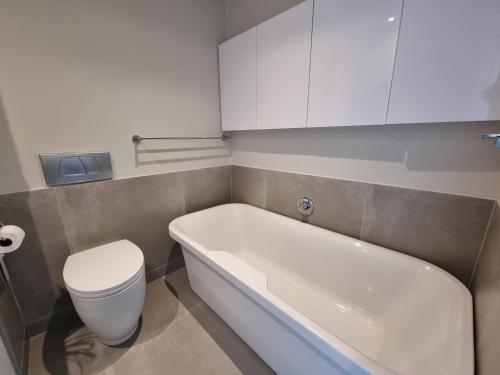 a bathroom with a toilet and a bath tub at Lagoon Shoreline 2 Bedroom Apartment in Cape Town