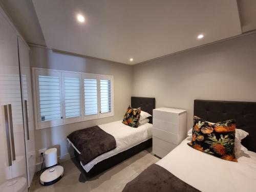 a bedroom with two beds and a window at Lagoon Shoreline 2 Bedroom Apartment in Cape Town