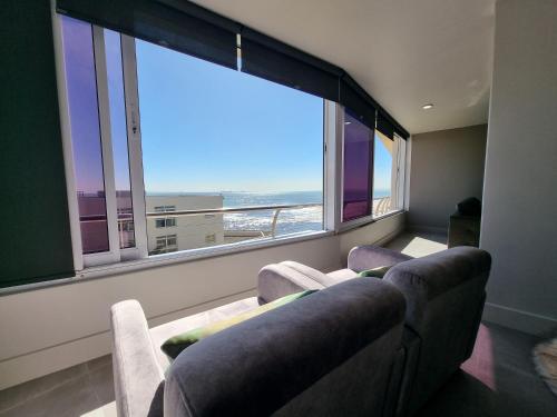 a living room with two couches and a large window at Lagoon Shoreline 2 Bedroom Apartment in Cape Town