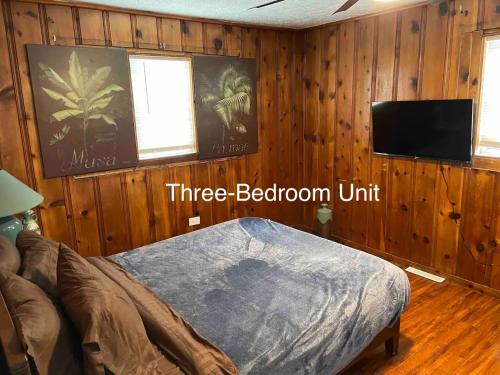 a bedroom with wood paneling and a bed and a flat screen tv at Derby City Getaway in Louisville