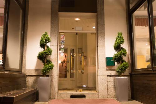 um edifício com dois vasos de plantas na frente de uma porta em Hotel Terminus em Saint-Gervais-les-Bains