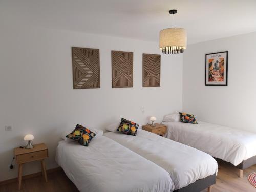 two beds in a room with white walls at Logis Hôtel Restaurant Cruzel in Maurs