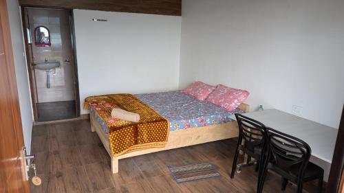 ダージリンにあるGreenwood Homestays, Rohiniの小さなベッドルーム(ベッド1台、テーブル、椅子付)