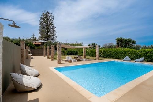 una piscina en un patio trasero con sillas y cenador en Villa Hyacinthe by A&D Properties, en Porto Rafti