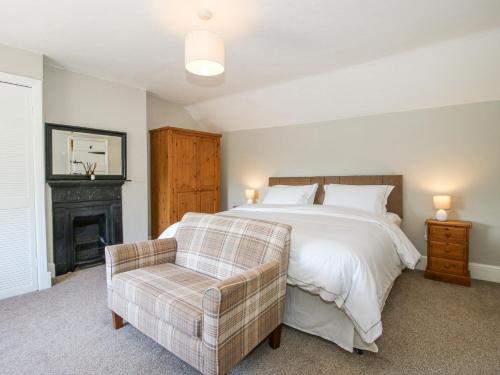 ein Schlafzimmer mit einem großen Bett und einem Stuhl in der Unterkunft Pennal Cottage in Oswestry