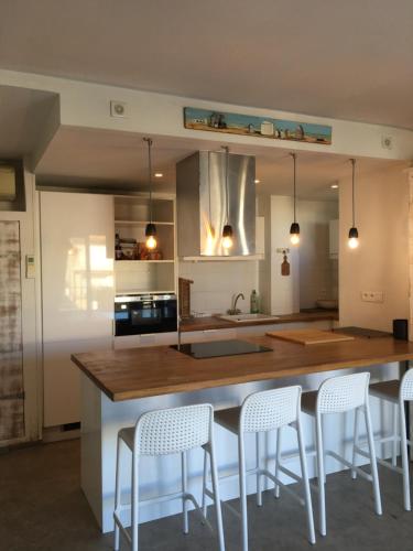 une cuisine avec un bar et des tabourets blancs dans l'établissement Acces Direct Plage, Vue Mer, Climatisation, à La Celle-sous-Gouzon