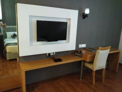 a room with a desk with a television on a wall at Maha Bodhi Hotel.Resort.Convention Centre in Bodh Gaya
