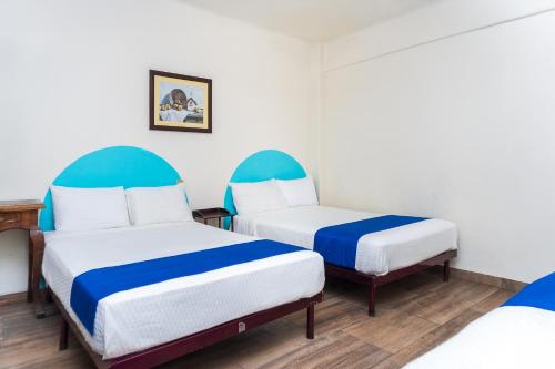 two beds in a room with blue and white at Capital O Nueva York, Guadalajara centro downtown in Guadalajara