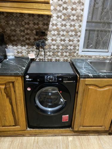 a black washing machine in a kitchen with a sink at Dalal Jamu in Serekunda