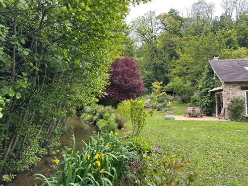 un jardin avec un ruisseau en face d'une maison dans l'établissement Maison du Pré — Familial & Nature, à Bully