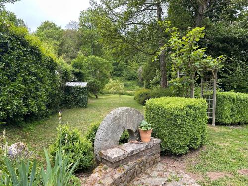 un banc de pierre dans un jardin avec des buissons et des arbres dans l'établissement Maison du Pré — Familial & Nature, à Bully