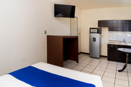 a room with a kitchen with a bed and a refrigerator at Capital O Nueva York, Guadalajara centro downtown in Guadalajara