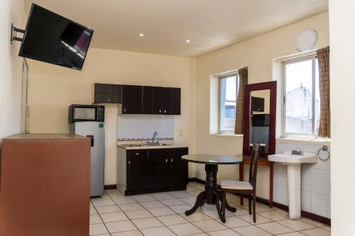 a kitchen with a small table and a refrigerator at Capital O Nueva York, Guadalajara centro downtown in Guadalajara