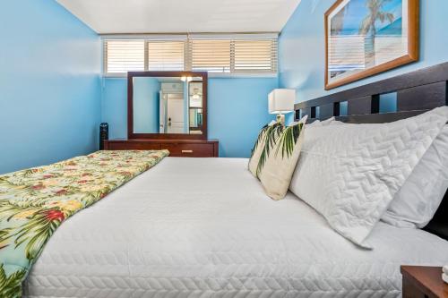 a bedroom with a large white bed with blue walls at Kahana Reef 120 by Coldwell Banker Island Vacations in Kahana