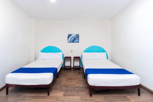 a row of beds in a room with white walls at Capital O Nueva York, Guadalajara centro downtown in Guadalajara