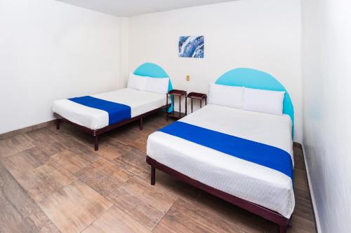 a room with two beds and two chairs at Capital O Nueva York, Guadalajara centro downtown in Guadalajara