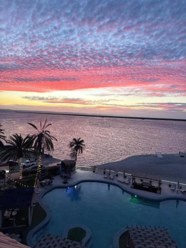 a swimming pool with a view of the ocean at sunset at La Posada Hotel Boutique in La Paz