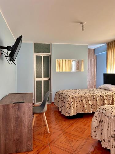 a bedroom with two beds and a chair and a table at Hospedaje in Ayacucho