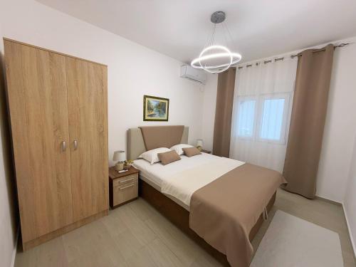 a bedroom with a large bed and a wooden cabinet at Apartmani Avanti Becici in Becici