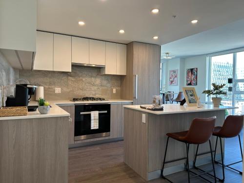 a kitchen with white cabinets and a counter with stools at UBC Pacific Spirit Modern Style Home in Vancouver