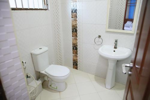 a white bathroom with a toilet and a sink at Nyali Fully Furnished Rooms With Swimming pool in Mombasa